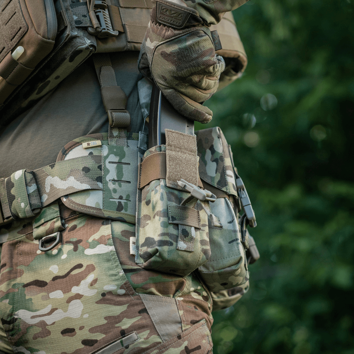 Henkilö kantaa M-Tac kaksiosaista lippastaskua Fastex-lukolla maastokuviossa, sotilas- ja ulkoilukäyttöön