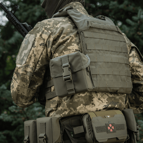 M-Tac PVS-14 -yönäkölaitteen laukku kiinnitettynä sotilaan univormuun metsäympäristössä.