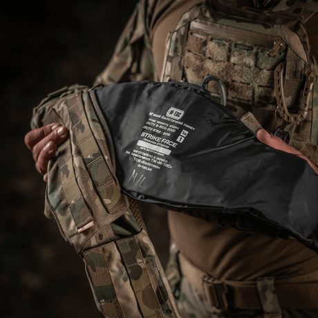Henkilö pitää M-Tac War Belt ARMORia, jossa MOLLE-webbing ja kestävät materiaalit, sopii taktiseen käyttöön.