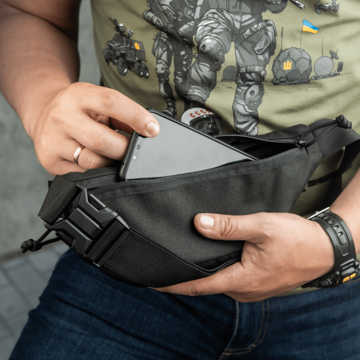 M-Tac Tactical Waist Bag Gen.II Elite käytössä älypuhelimen säilytykseen; sopii taktiseen käyttöön ja arkeen, valmistettu kestävästä Cordura 1000D:stä.