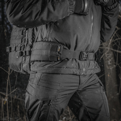 M-Tac Rygsæk Gen.II Elite Large kantajana henkilö talvivaatteissa metsässä, valmistettu kestävästä Cordura-materiaalista maksimaalista kestävyyttä varten.