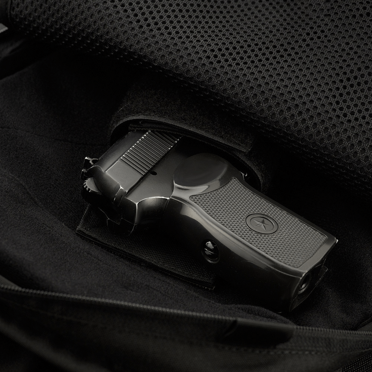 Laukun sisätila M-Tac Magnet XL Bag Elite -laukussa universaaliholsterilla, kuvassa pistooli, korostaa laukun toiminnallisuutta ja turvallisuutta.