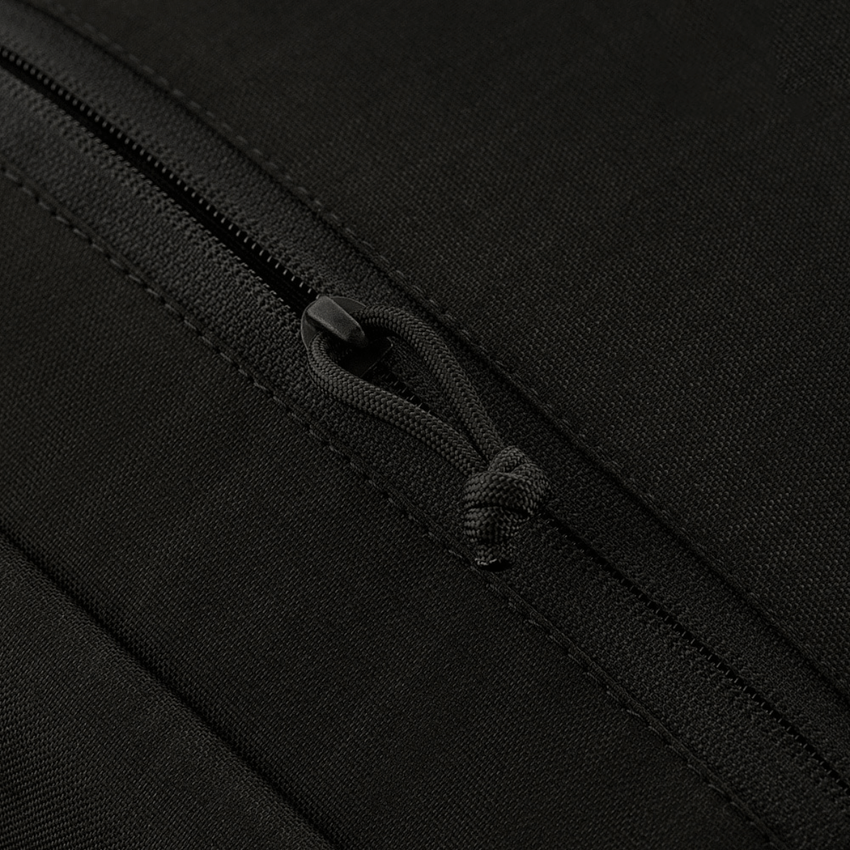 Lähikuva M-Tac Magnet XL Bag Elite -laukun vetoketjun yksityiskohdasta mustassa kankaassa.
