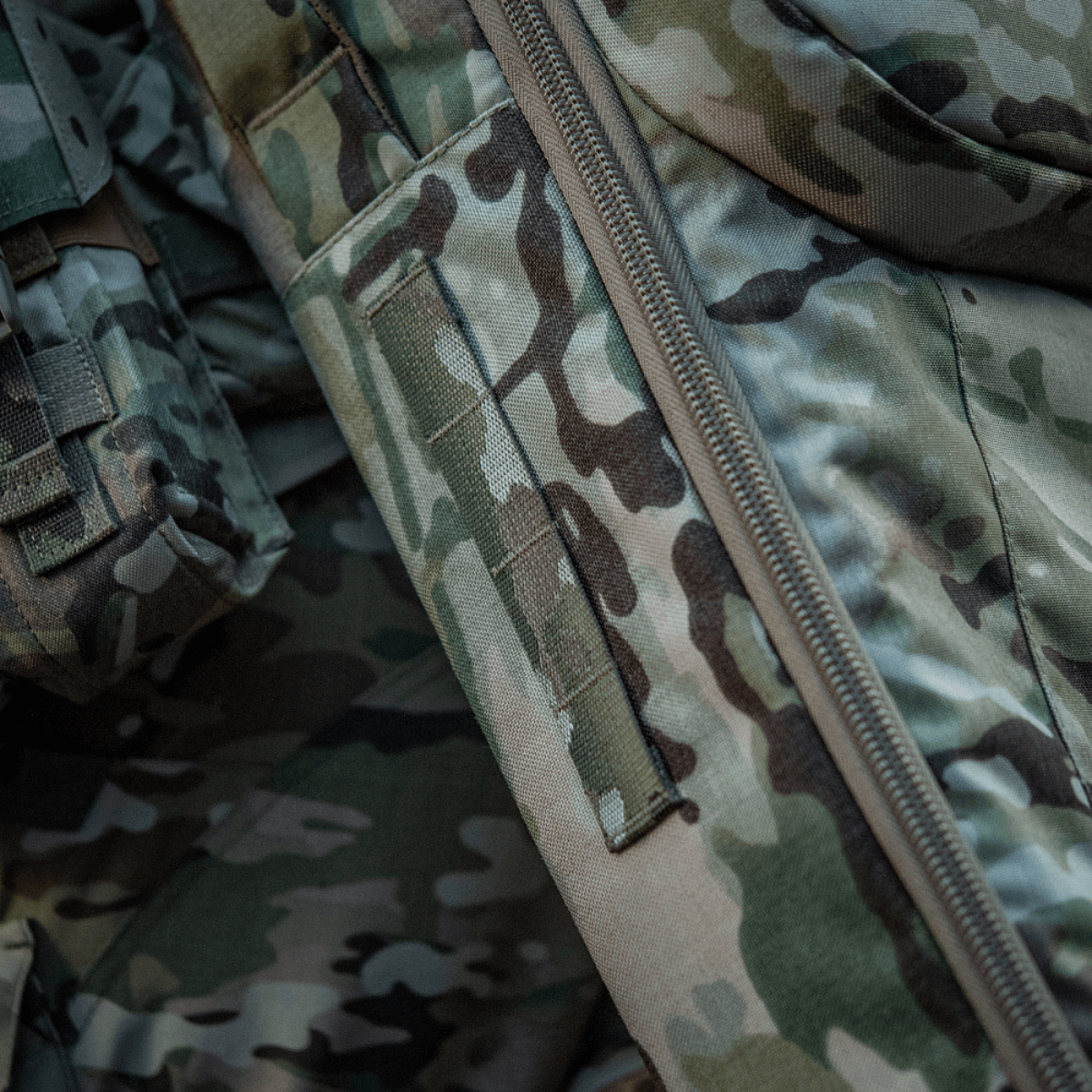 Yksityiskohta M-Tac Gun Backpack Case 125 cm Gen.II Elite:stä camokankaassa, korostaa Cordura-materiaalia ja vetoketjua
