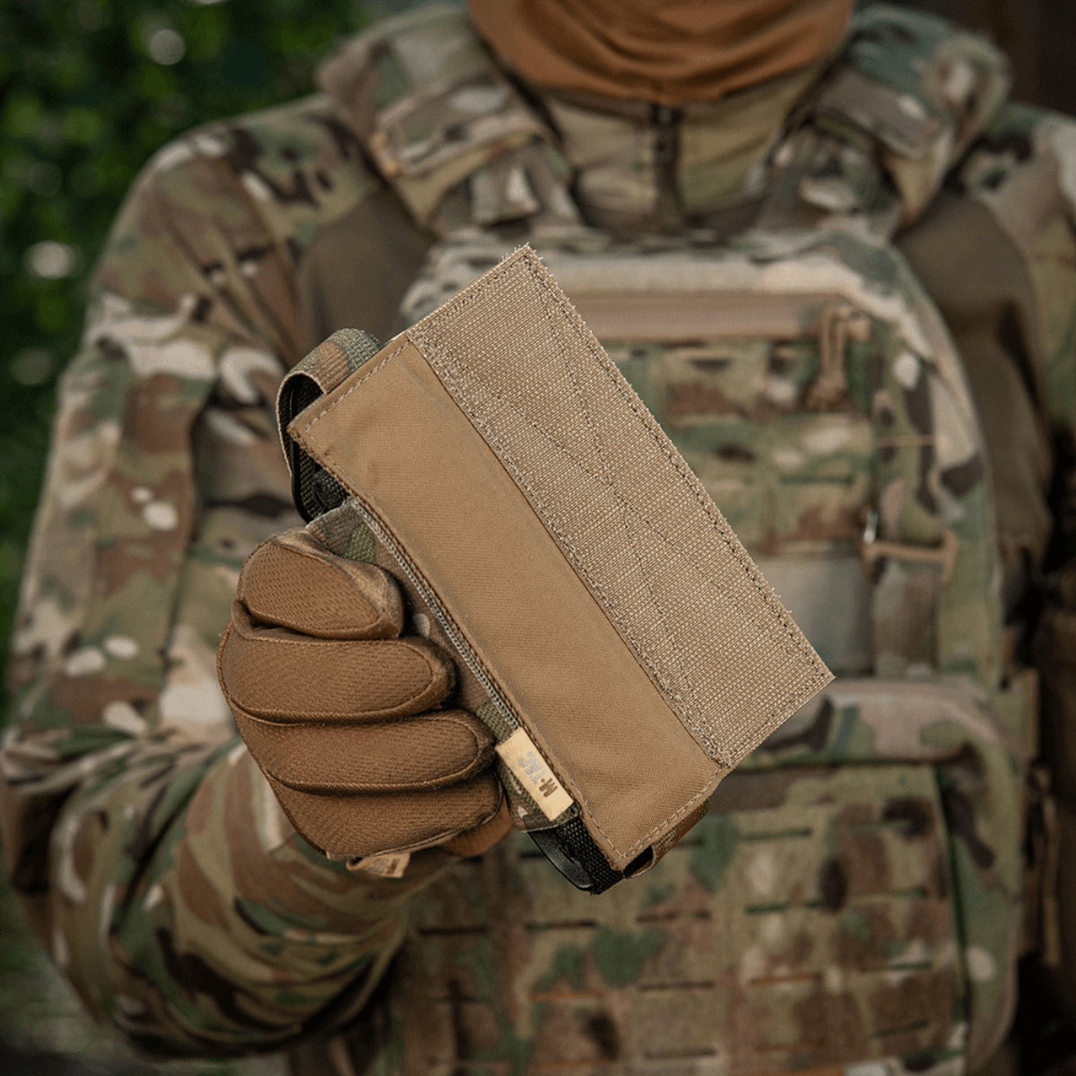 M-Tac Tourniquet Pouch Elastisk VELCRO Gen.II maastoympäristössä, pidetty taktisen varustuksen kantajan toimesta