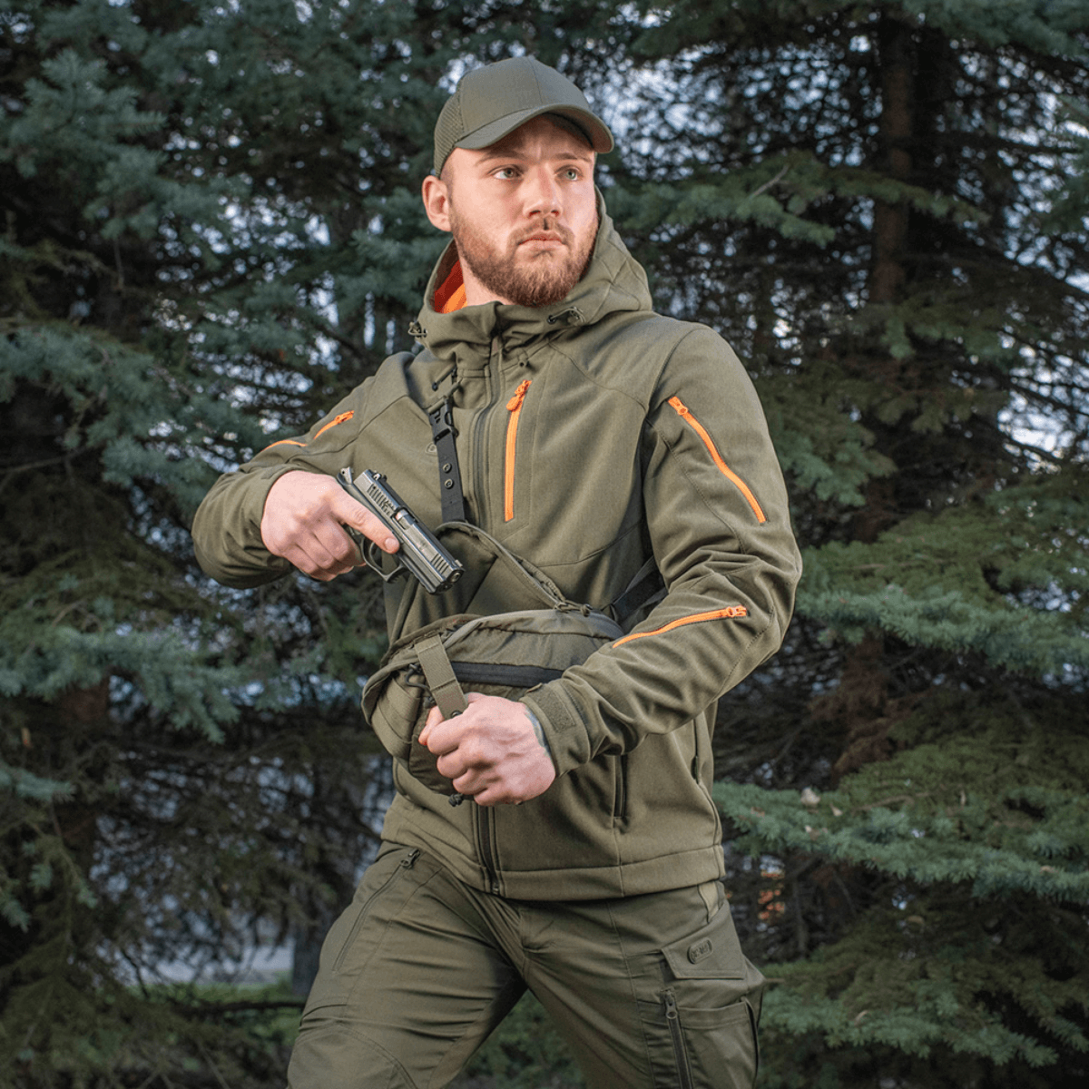 Mies kantaa M-Tac Sphaera Hex Hardsling Gen.II Elite -laukkua metsässä, valmis nopeaan toimintaan piilotetulla kantojärjestelmällä.