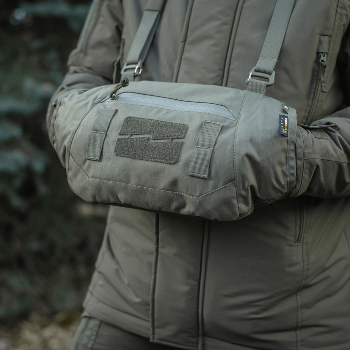 Henkilö käyttää harmaata M-Tac Taktisk Håndvarmer Eliteä, valmistettu Cordurasta Polartec-fleecevuorella, sopii kylmään säähän