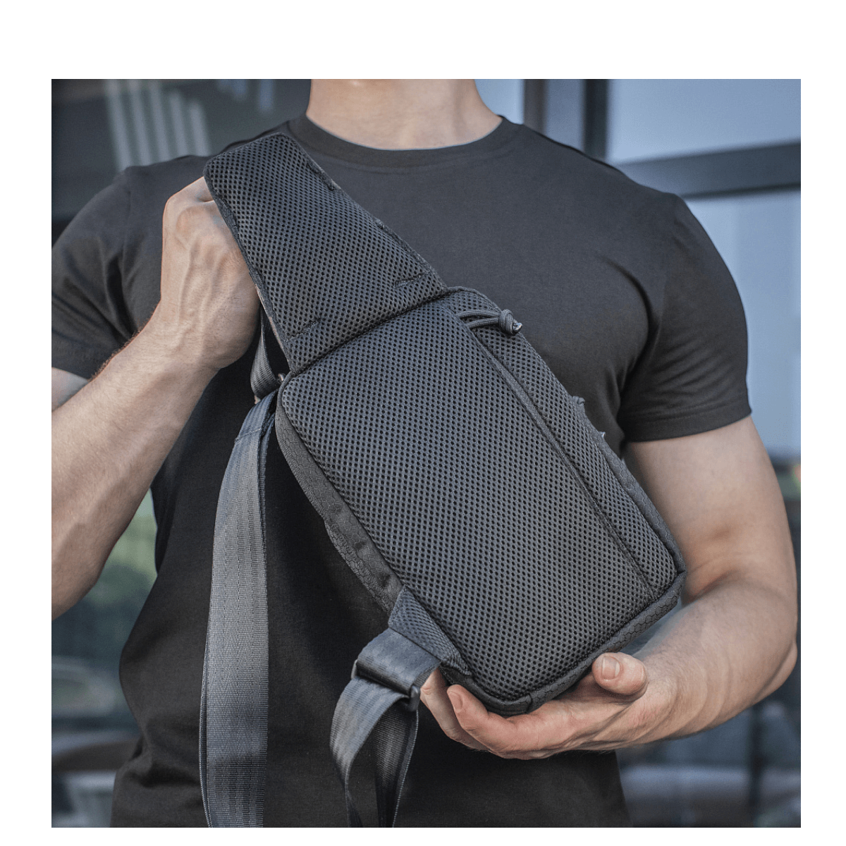 Henkilö kantaa M-Tac Sling Pistoltaske Elite Hexiä, mukava ja kestävä laukku säädettävällä olkahihnalla ja kestävästä materiaalista.