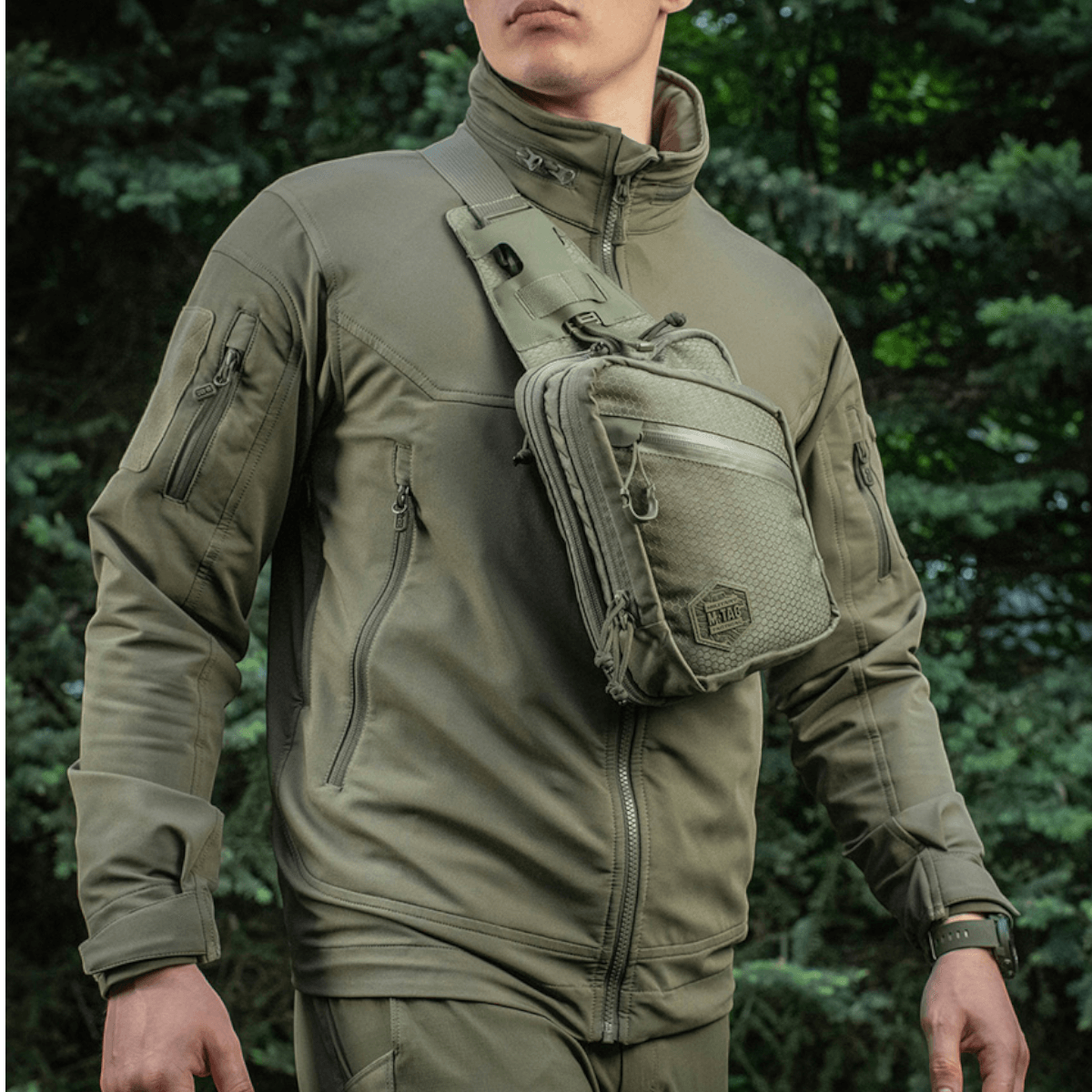 Mies, jolla on M-Tac Sling Pistoltaske Elite Hex, monipuolinen ja tyylikäs laukku piilotetulle aseelle, valmistettu Cordura 1000D -materiaalista.