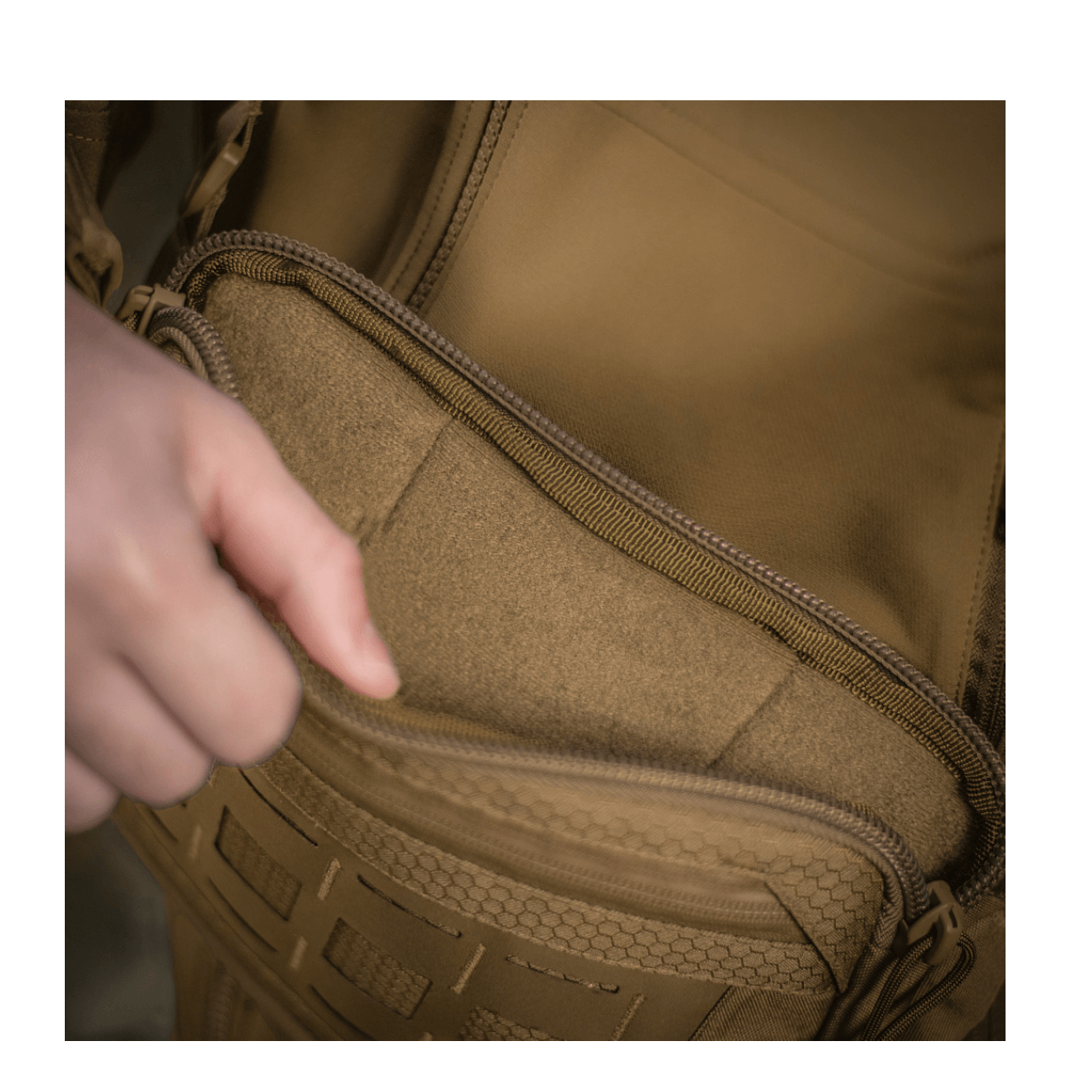 Henkilö avaa taskun M-Tac Admin-laukusta Elite, kestävä Cordura-materiaali ja YKK-vetoketjut