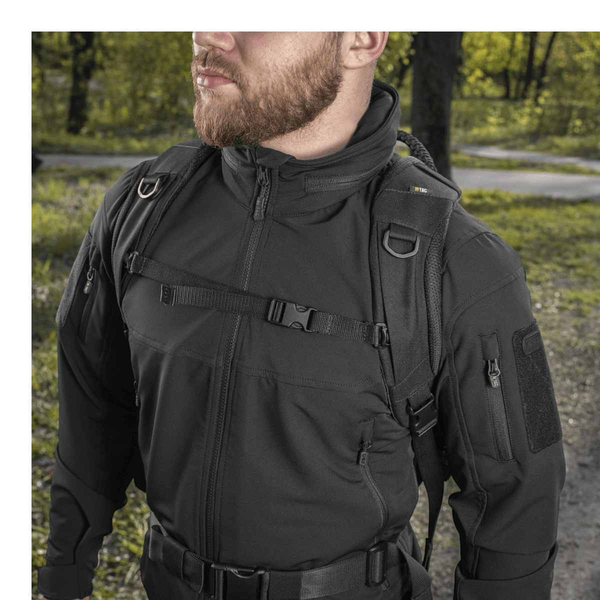 Mies kantaa M-Tac Mission Pack Elite -reppua metsäalueella, korostaen Cordura 1000D -kankaan tyylikästä muotoilua.