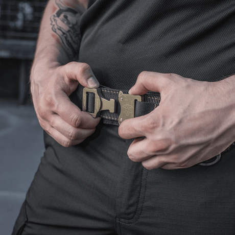 Mies säätää M-Tac taktista vyötä Cobra-soljella kestävällä nailonilla, ihanteellinen sotilaskäyttöön ja holster-vyöksi.