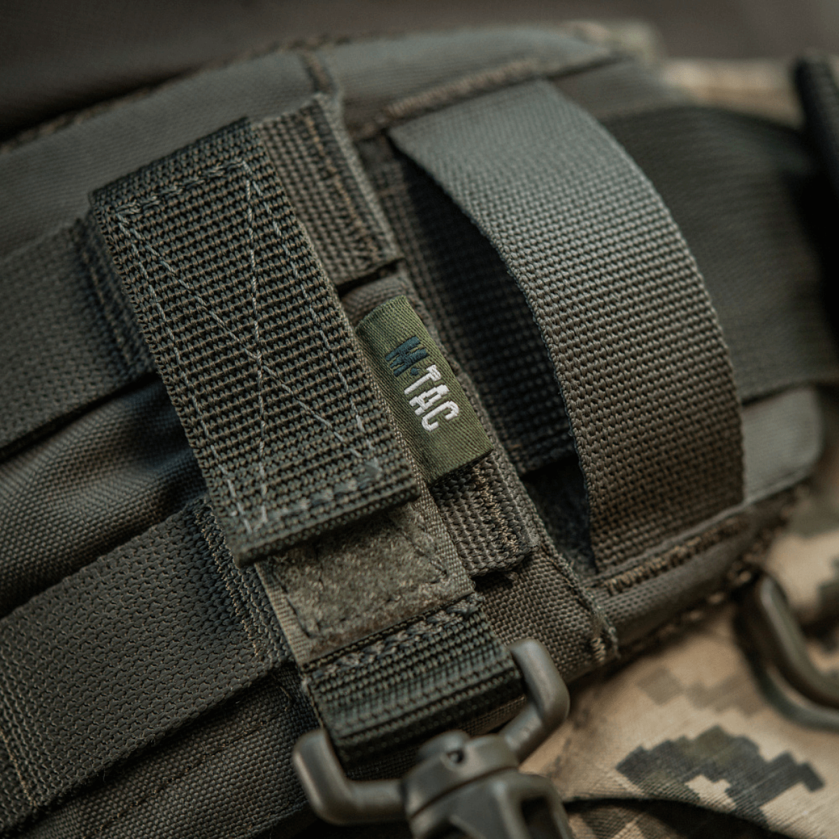 M-Tac karabiinihaka-lisävaruste kiinnitetty MOLLE-järjestelmään Velcro-remmillä, täydellinen taktiseen varustukseen, kevyt ja kompakti muotoilu.