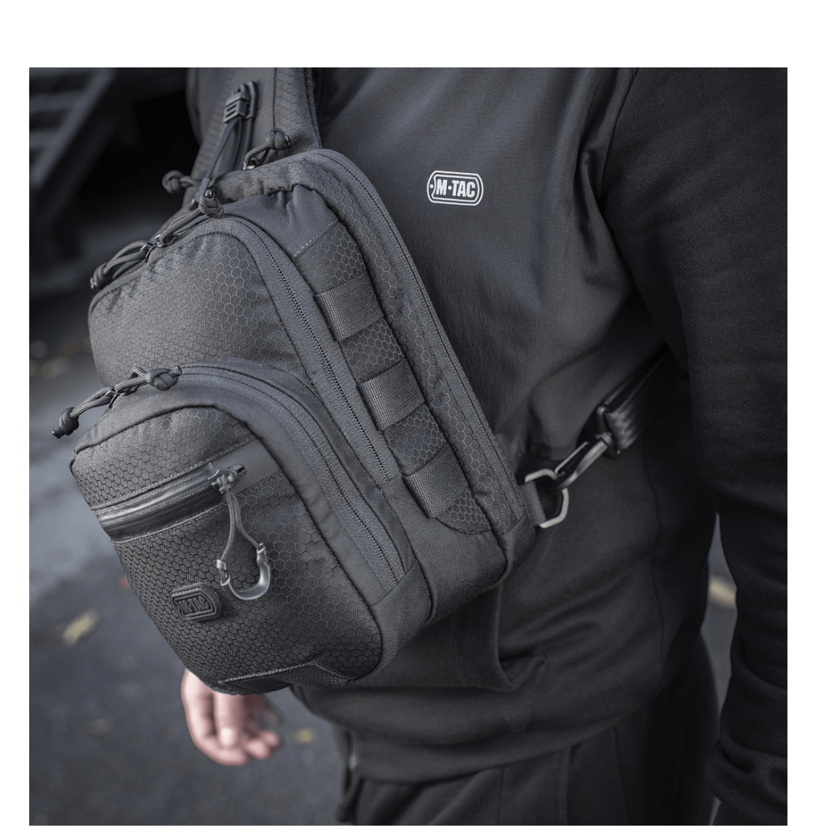 M-Tac Cross Taske Slim Elite Hex kannettuna olalla, näyttää tyylikkään muotoilun ja kestävän Cordura-kankaan.