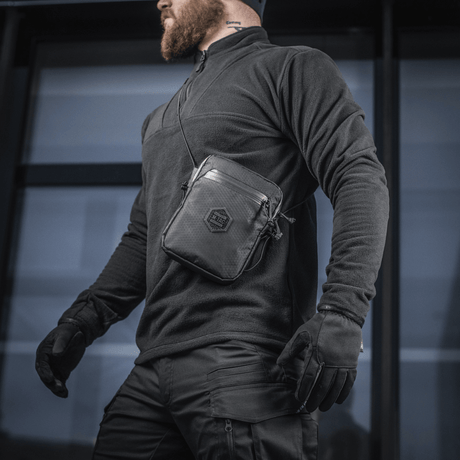 M-Tac Pocket Bag Elite HEX miehen kantamana, sopii kompaktiksi säilytykseksi EDC-varusteille, kulutusta kestävä materiaali ja YKK-vetoketjut.