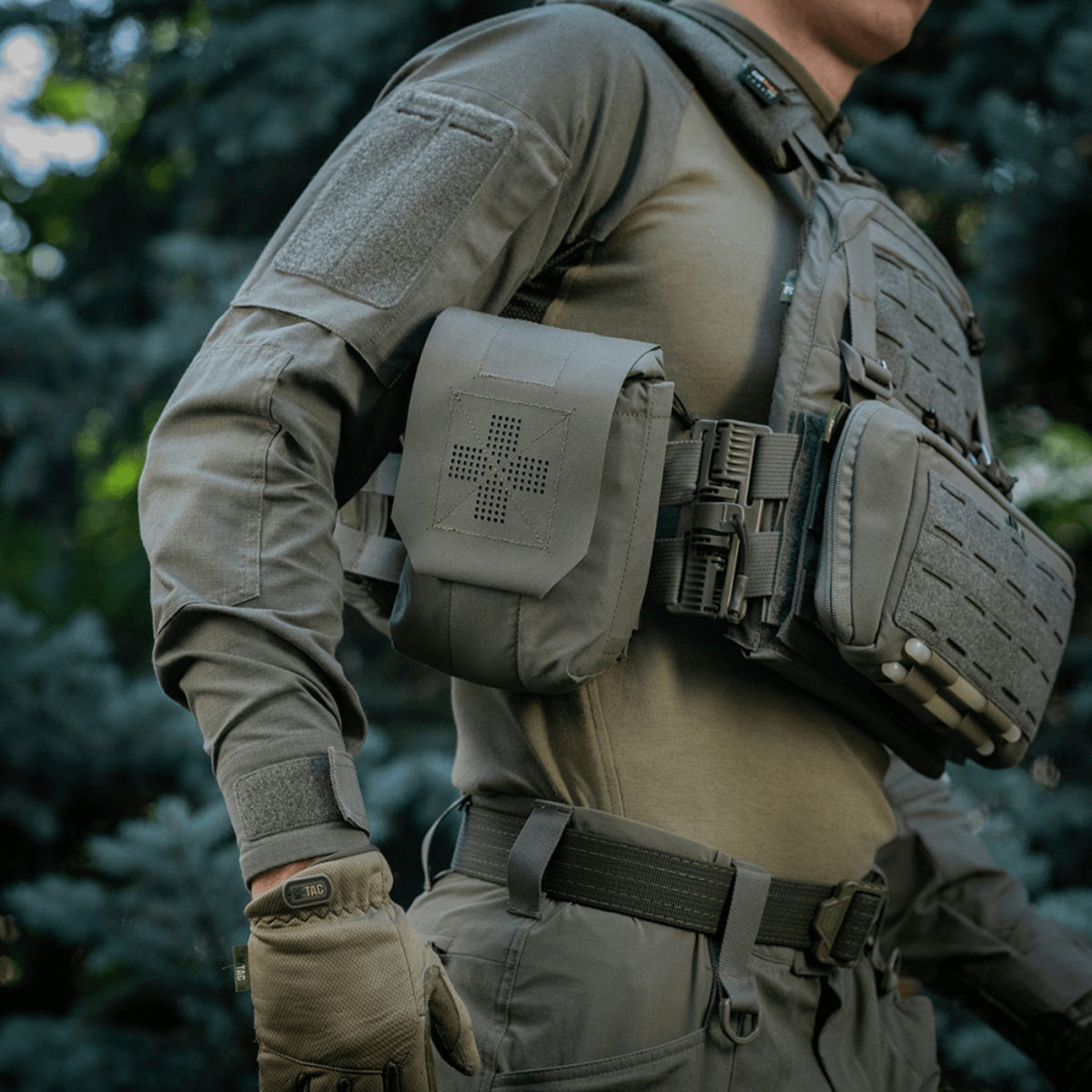 M‑Tac Medic Pouch Vertical Large Elite kiinnitettynä taktiseen liiviin ulkona, valmistettu kestävästä Cordura 500D -materiaalista turvallista säilytystä varten.