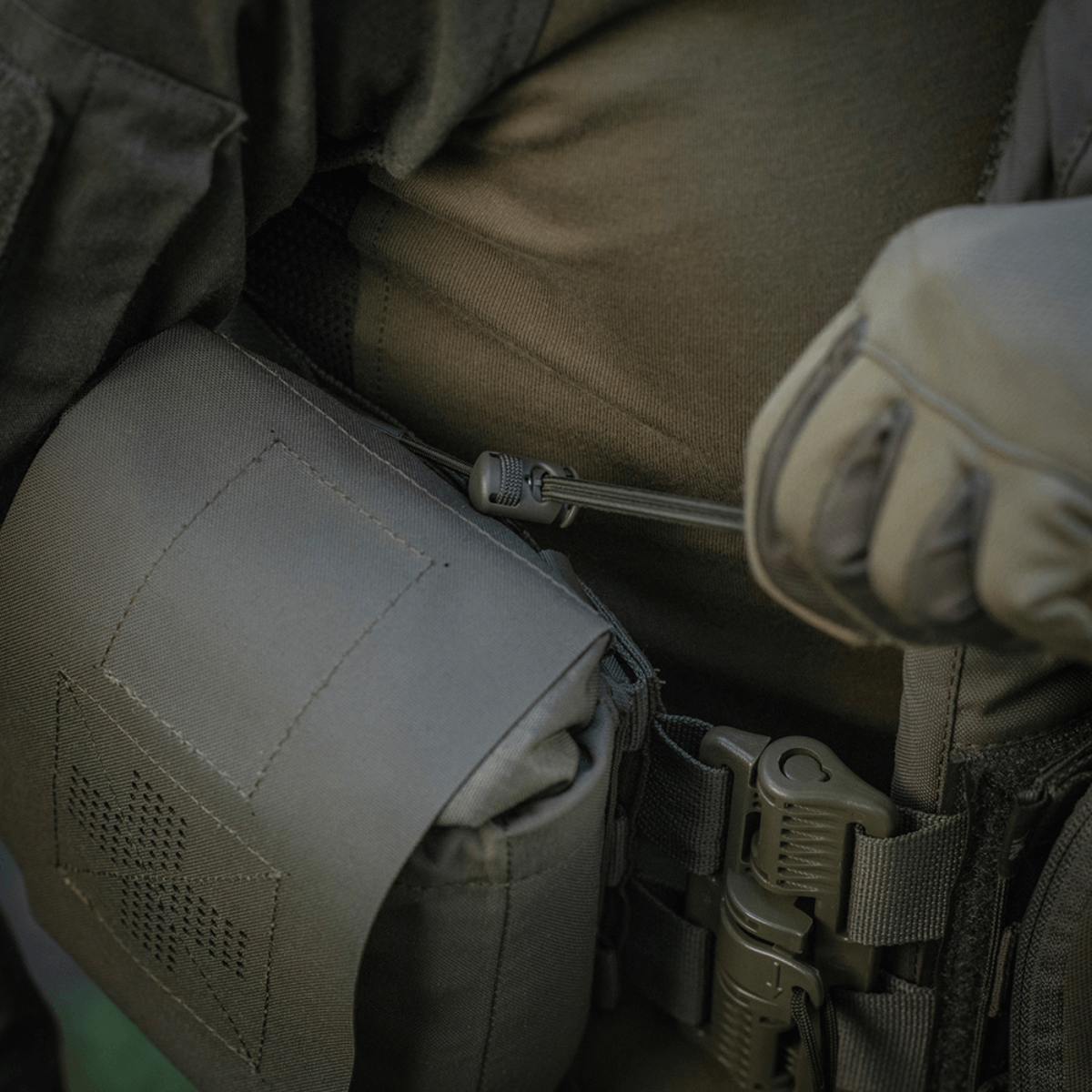 M‑Tac Medic Pouch Vertical Large Elite kiinnitettynä taktiseen varusteeseen, valmistettu kestävästä Cordura 500D:stä, näyttää lääkinnällisten välineiden turvallisen säilytyksen.