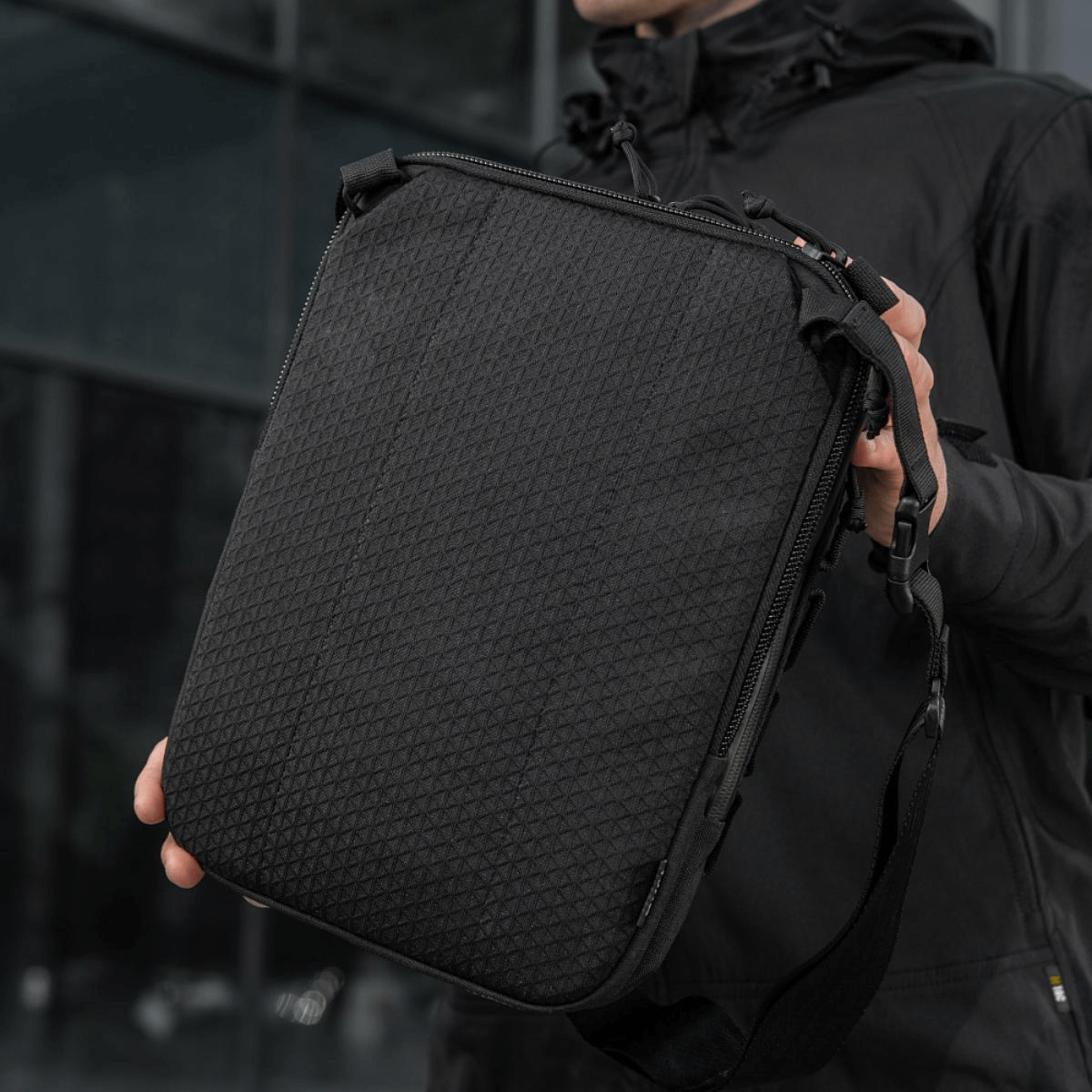 M-Tac Tablet Bag Laser Cut Hex, käytännöllinen Cordura-laukku Laser Cut MOLLE:lla ja piilotetulle aseelle tarkoitetulla lokerolla, nähty kädessä.