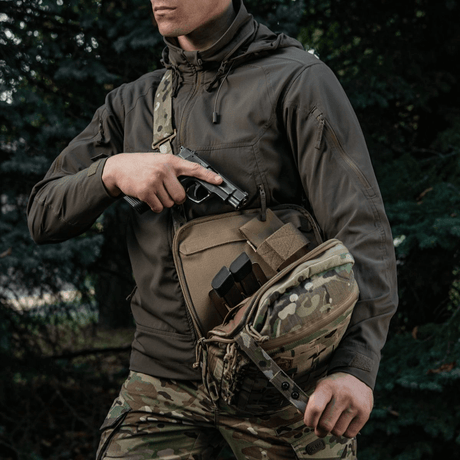 M-Tac Tablet Bag Laser Cut Hex piilotetun asekotelon ja nopean pääsyn kanssa, camokuvio, mies taktisiin vaatteisiin pukeutuneena.