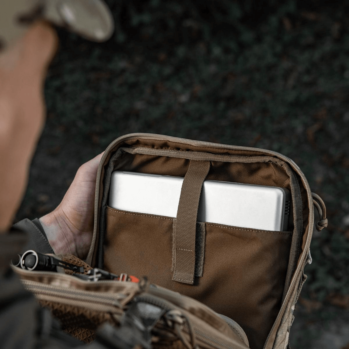Henkilö avaa M-Tac Tablet Bag Laser Cut Hex -laukkuun, sisältää tabletin ja asiakirjoja.