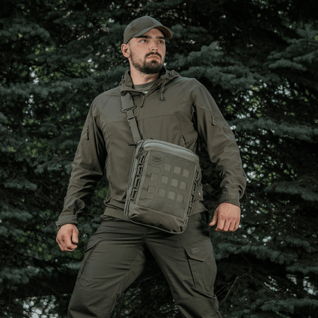 Henkilö M-Tac Tablet Bag Laser Cut Hex -laukulla metsämiljöössä.