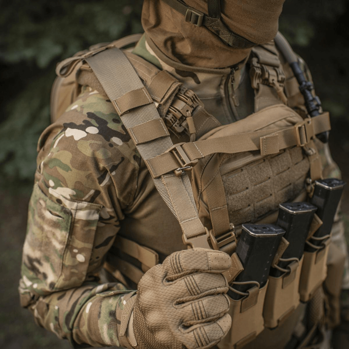 Henkilö pukeutuneena taktiseen varustukseen M-Tac STURM Elite -repun kanssa metsäympäristössä.