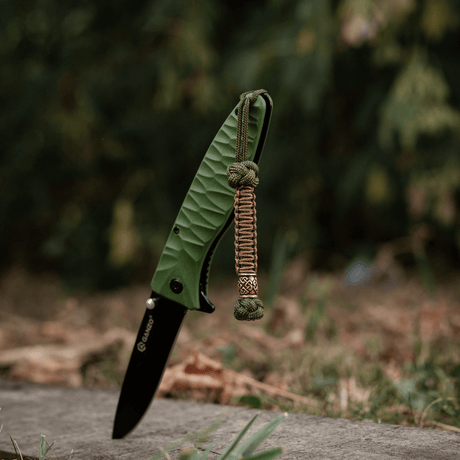 M-Tac Knife Lanyard Celtic, punottu paracord-lanka kiinnitetty vihreään veitsen, ulkoilmahenkinen ja käytännöllinen.