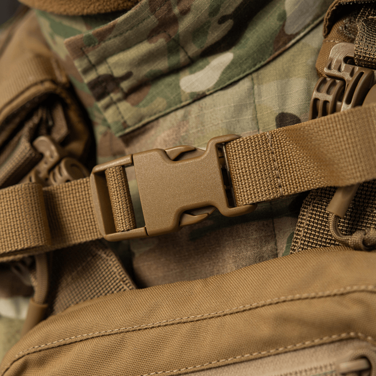 Lähikuva M-Tac reppu Sturm Elite Gen.II tukevasta soljesta ja maastotaustasta, ihanteellinen taktisiin toimiin.