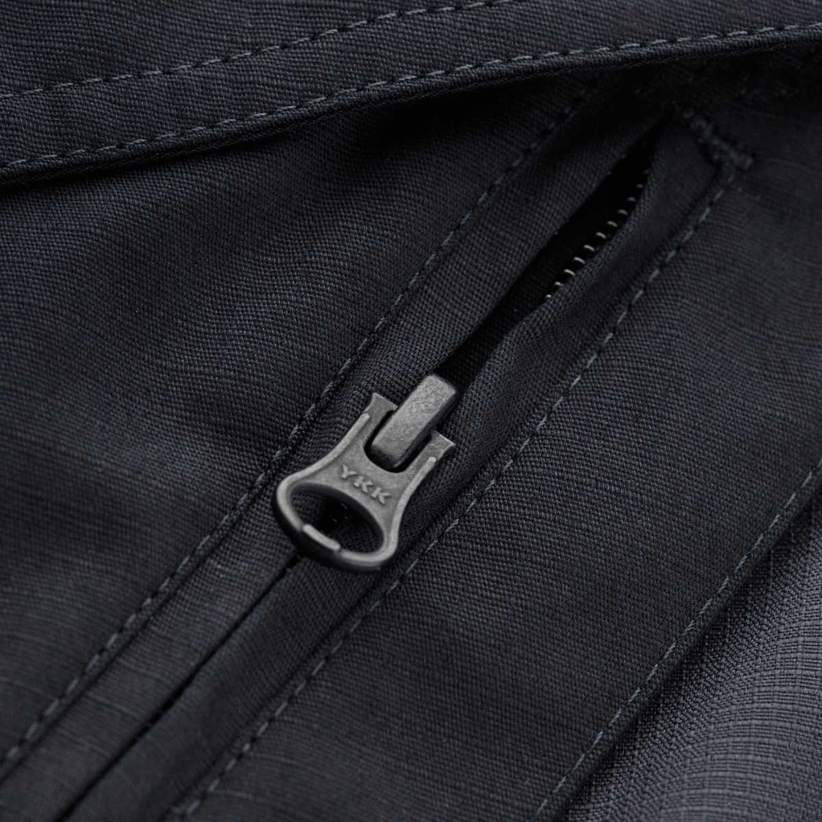 Lähikuva vetoketjutaskusta M-Tac Shorts Aggressor Gen.II Flexissä, valmistettu kestävästä ripstop-kankaasta Teflon-pinnoitteella.