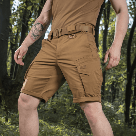 M-Tac Shorts Aggressor Gen.II Flex ruskeana ripstop-materiaalista, sopii harjoitteluun ja vapaa-aikaan, esitetty metsässä.