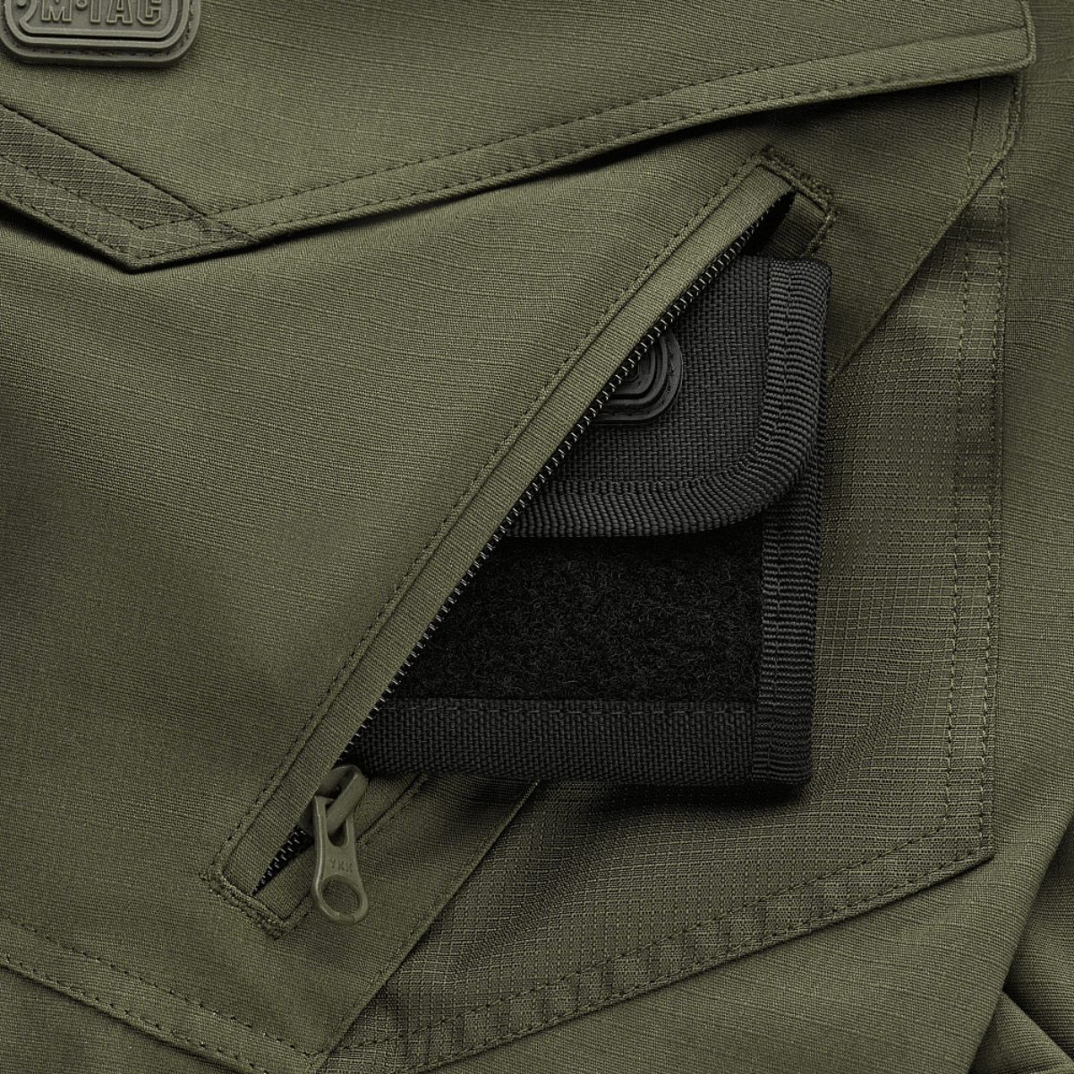 M-Tac Shorts Aggressor Gen.II Flex lähikuva taskusta oliivinvihreässä ripstop-materiaalissa vetoketjidetaljilla.