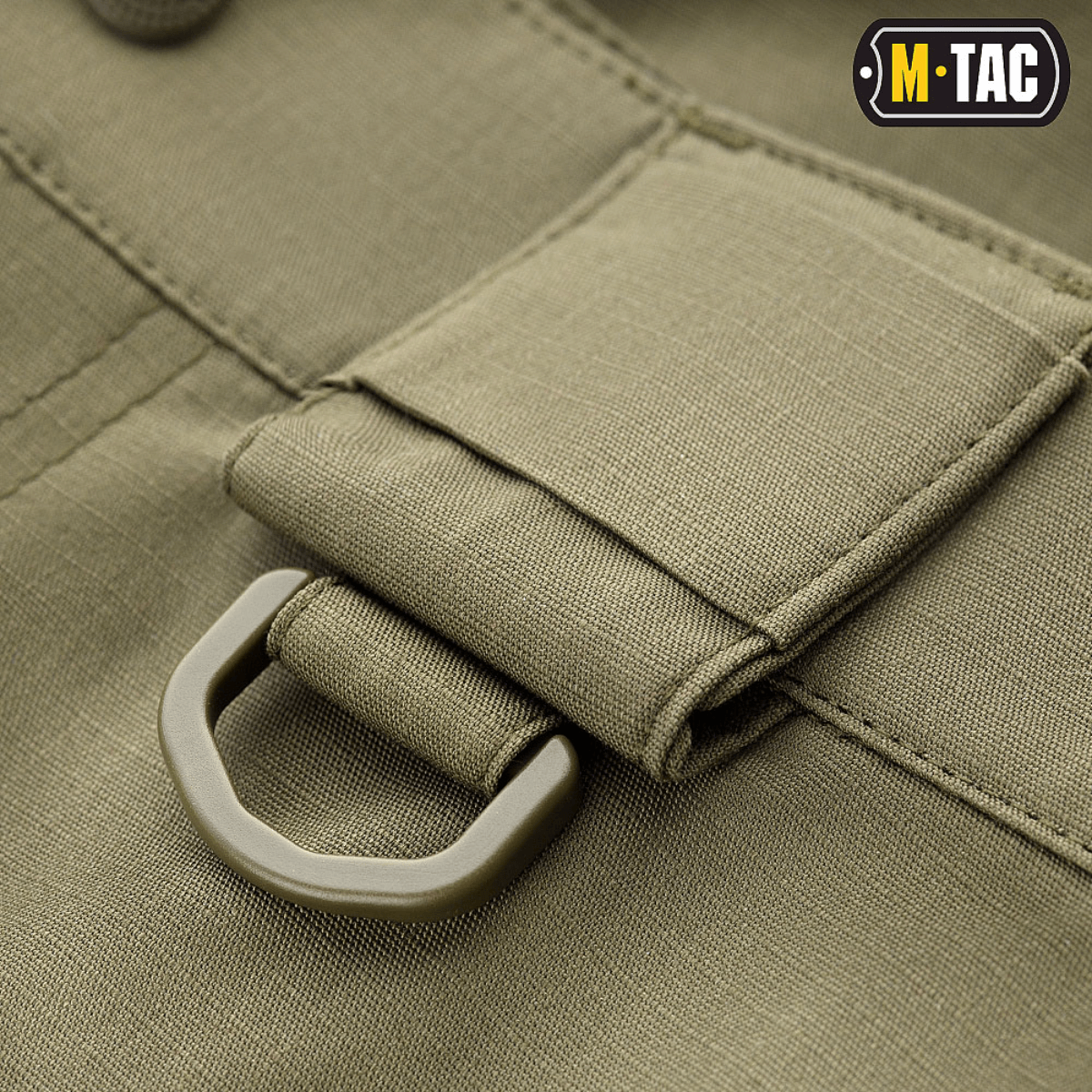 Yksityiskohta M-Tac Shorts Aggressor Shortista, D-rengas oliivinvihreässä rip-stop-kankaassa taktisten varusteiden kiinnitykseen