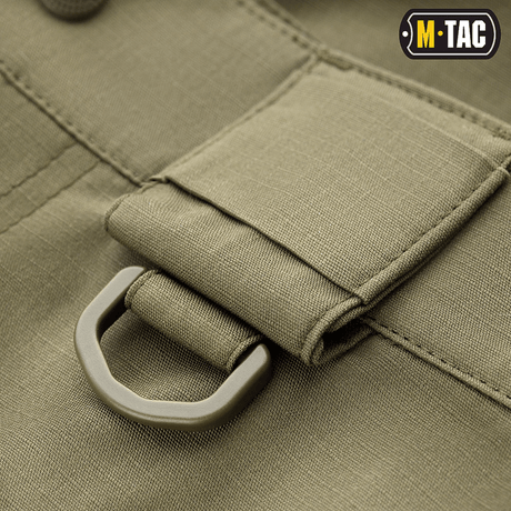 Yksityiskohta M-Tac Shorts Aggressor Shortista, D-rengas oliivinvihreässä rip-stop-kankaassa taktisten varusteiden kiinnitykseen
