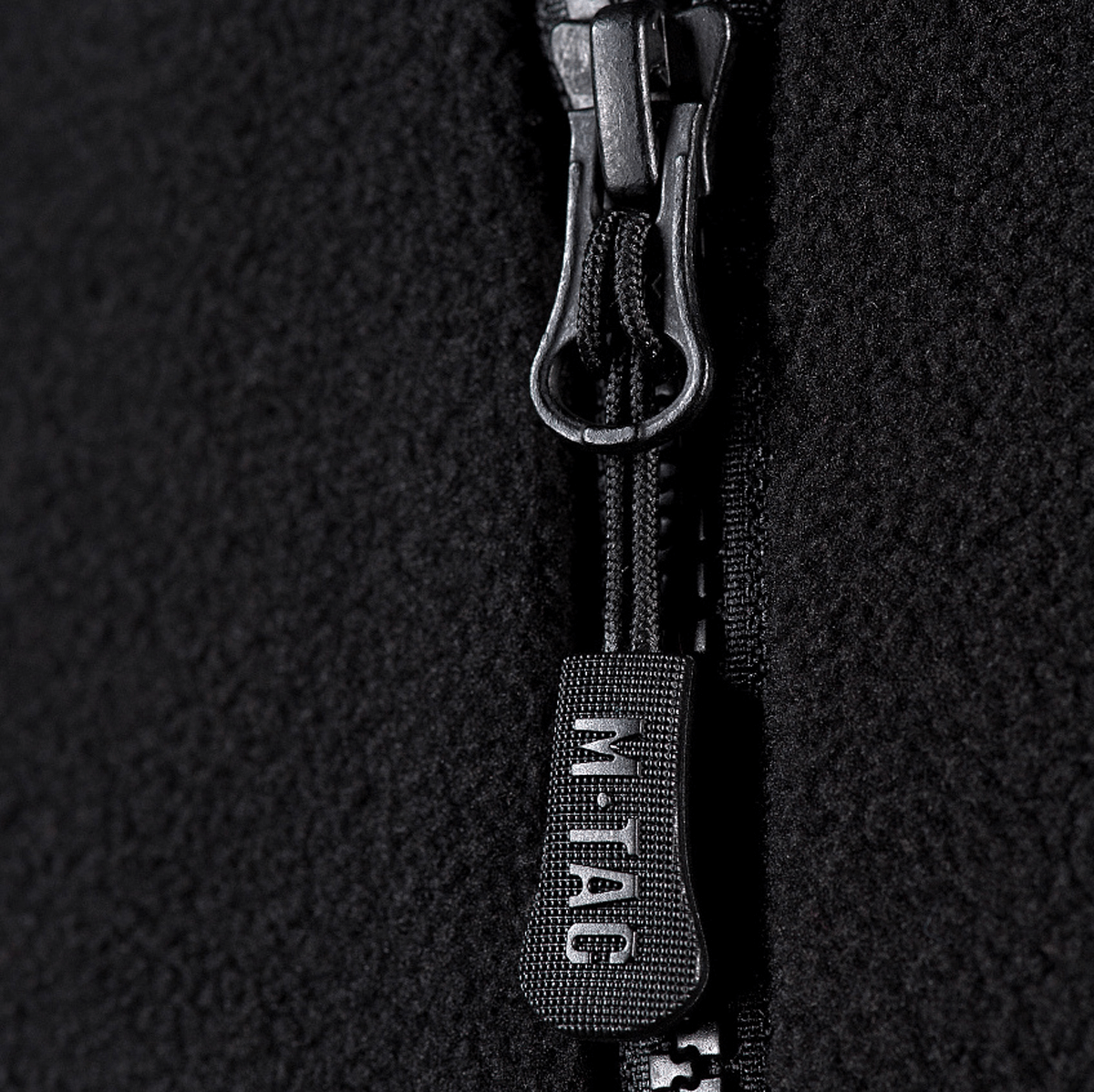 Lähikuva vetoketjusta M-Tac Lite Microfleece Hættetrøje, jossa M-Tac-logo vetoketjun vetimessä