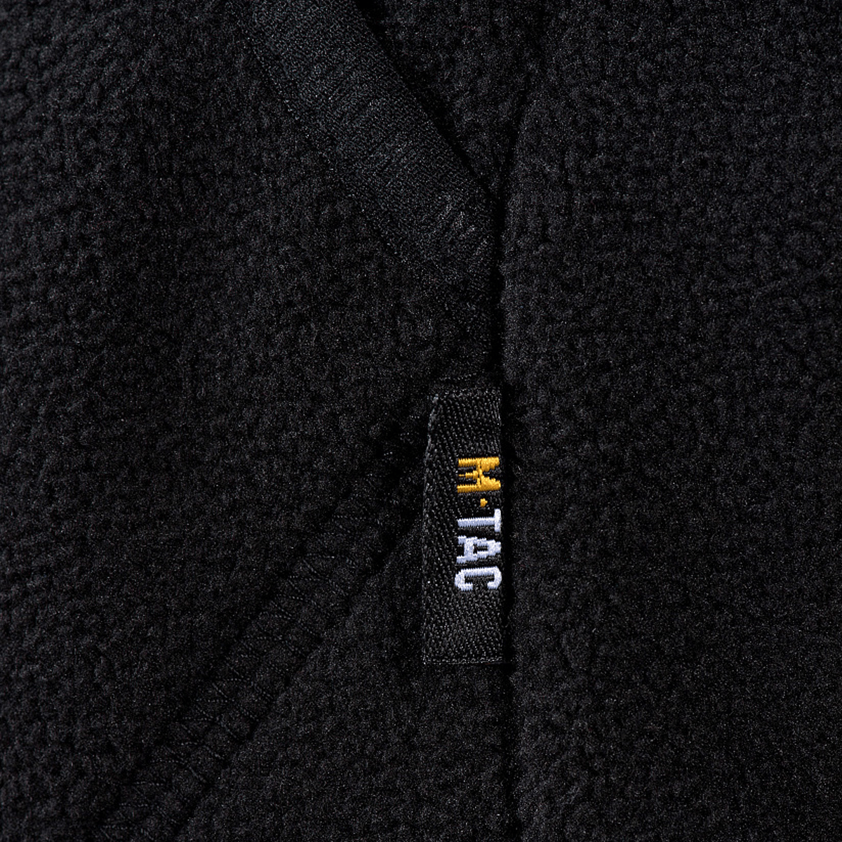 M-Tac Lite Microfleece Hættetrøje M-Tac-logolla reunustettuna elastisella nauhalla hyvään istuvuuteen. Musta mikrofleece, yksityiskohta