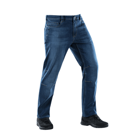 M-Tac Tactical Gen.I Regular Fit -farkut sinisessä denimissä valkoista taustaa vasten, mustien kenkien kanssa, näyttää farkkujen mallin ja istuvuuden.
