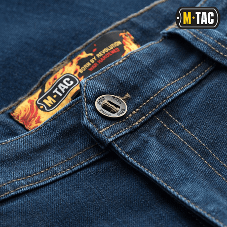 M-Tac Tactical Gen.I Regular Fit -farkut sinisessä denimissä, yksityiskohta napista ja logosta. Sopii taktiseen käyttöön ja arjen mukavuuteen.