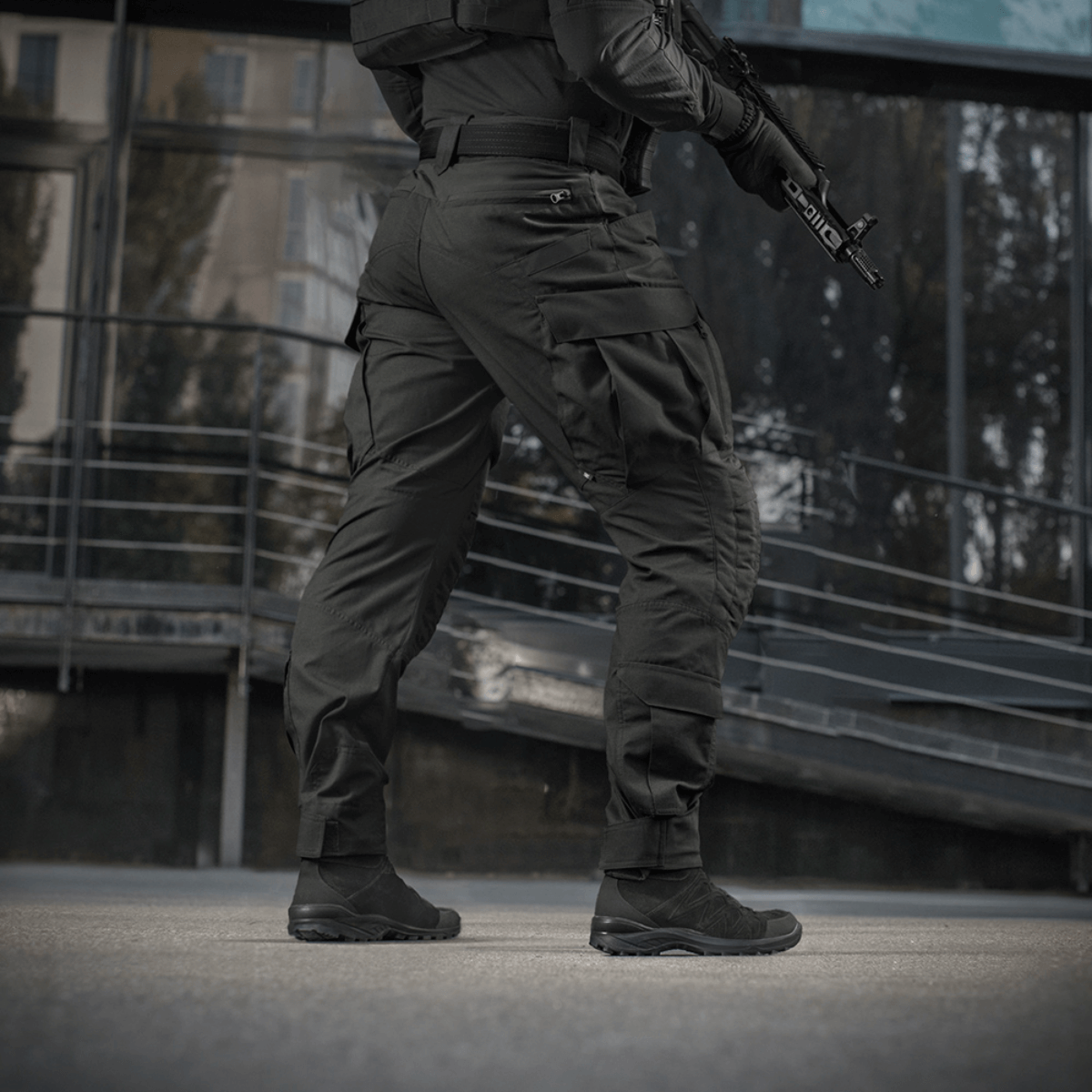Mies pitää yllä M-Tac STURM NyCo Extreme Gen.II -housuja joustavilla inserteillä, suunniteltu taktiseen käyttöön, kuvattu ulkona.