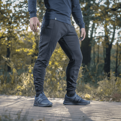 Mies pukeutuneena M-Tac Stealth Cotton -housuihin juoksuun ja arkeen. Puuvillakangas, kuminauha vyötäröllä, sivutaskut, mukavuuteen.