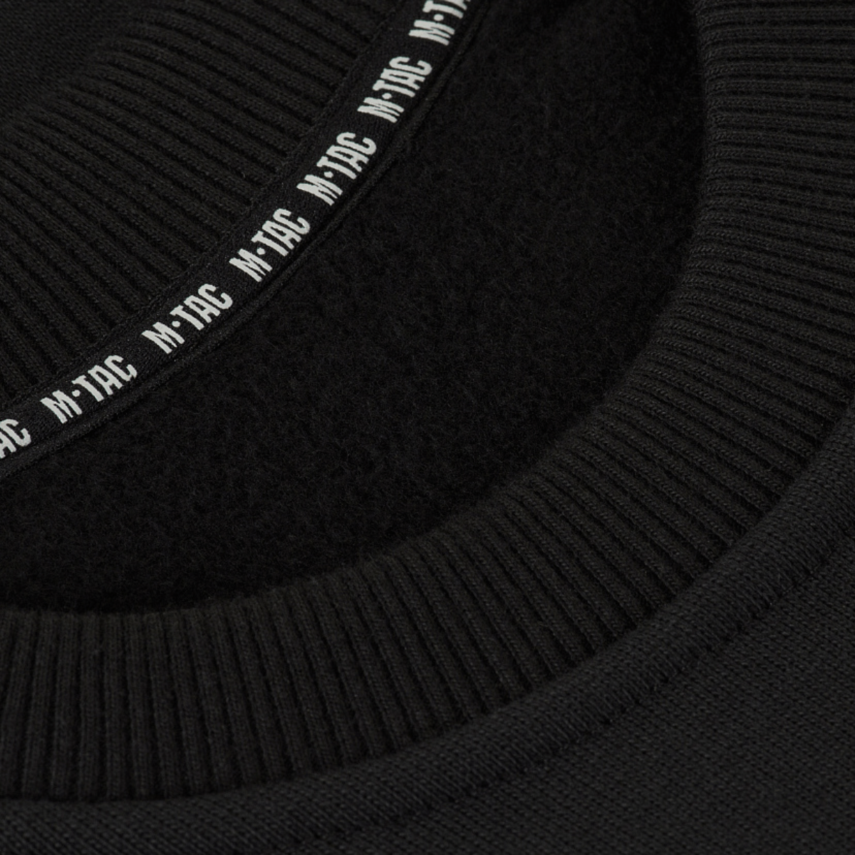 Yksityiskohta M-Tac Sweatshirt Cotton Hardista näyttää resorin ja heijastavan logon mustassa 100% puuvillamateriaalissa, tiheys 390 g/m².