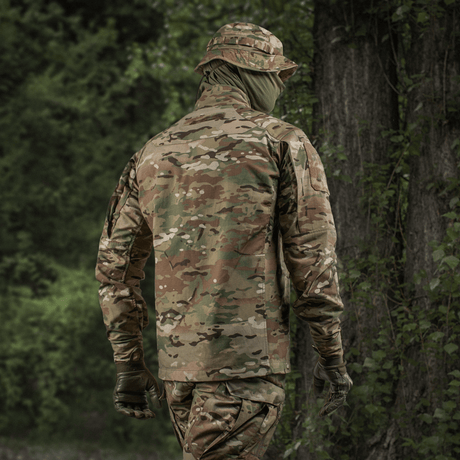 Henkilö pukeutuneena M-Tac Jakke Sturm NYCO Extreme Multicam-kuosissa metsässä.