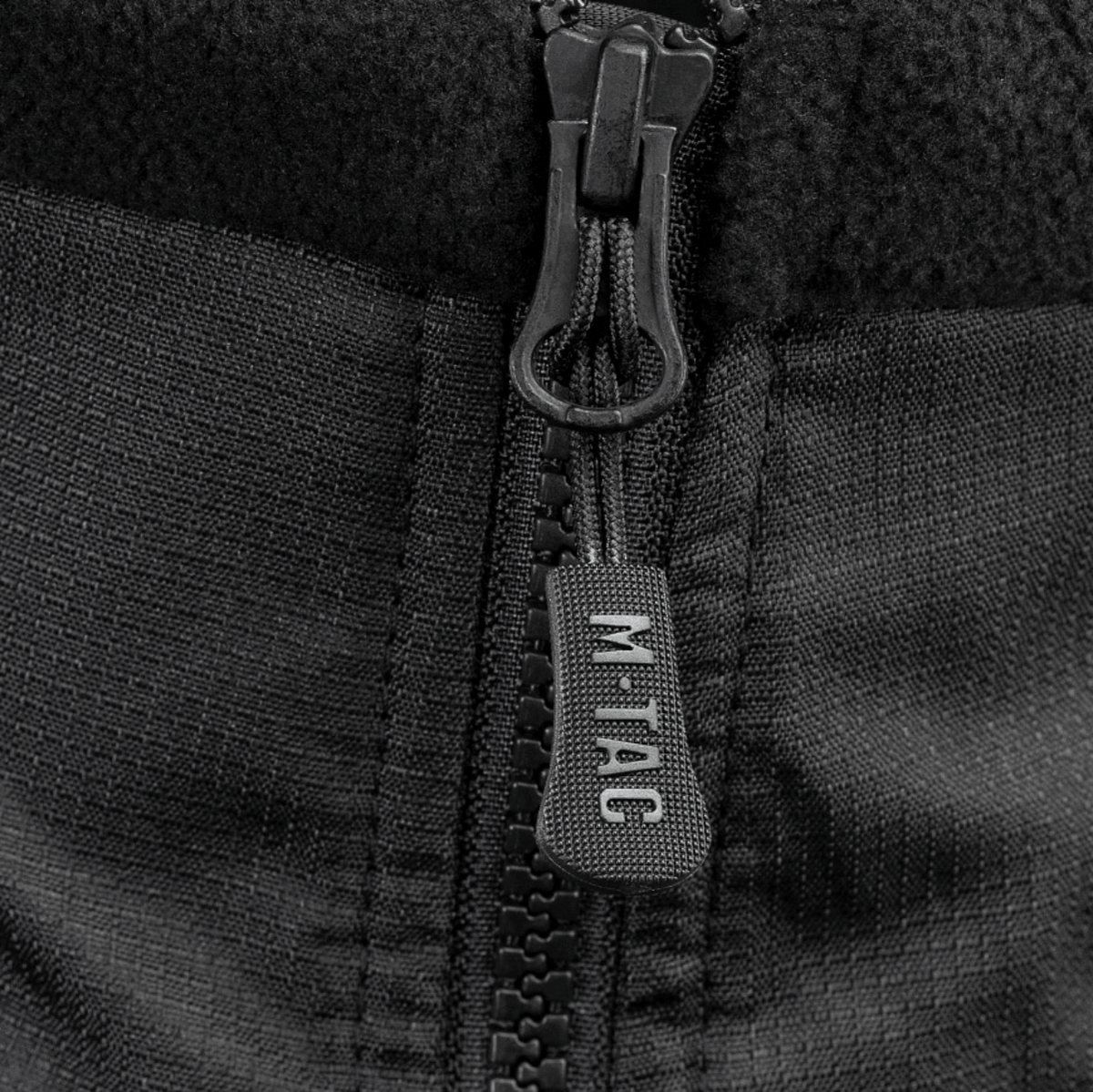 Lähikuva vetoketjusta M-Tac Alpha Microfleece Jakke Gen.II -takissa, näyttää tukevan rakenteen taktista ja ulkoilukäyttöä varten kylmällä säällä.