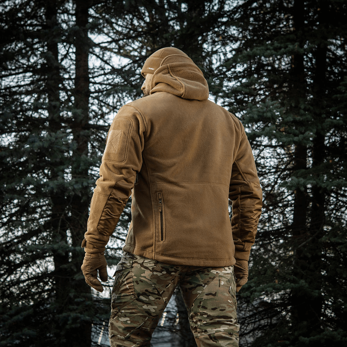 Mies pukeutuneena M-Tac Division Gen.II Windblock Fleecejakke metsässä, maksimaalinen lämpö ja tuulisuoja, 100% polyester.