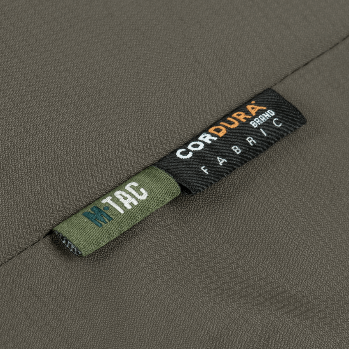 Lähikuva M-Tac Alpha Gen.III Pro talvitakista Cordura-kangaslabelilla, korostaa kestävyyttä ja laatua.