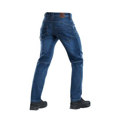 Takakuva M-Tac Jeans Tactical Gen. I Cordura Regular Fit, Cordura-denimhousut päivittäiseen ja taktiseen käyttöön, kuvattu saappaiden kanssa.