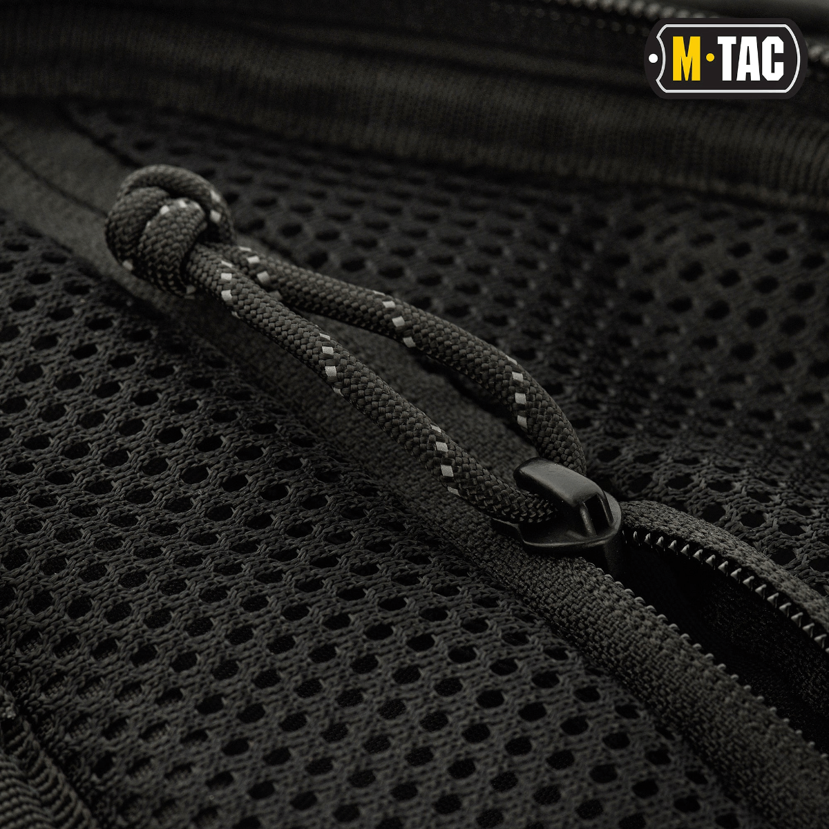 Lähikuva vetoketjusta ja rakenteesta M-Tac Buckler Taske Elite -laukun mustassa Cordura 500D -materiaalissa, näyttää yksityiskohtaisen muotoilun.