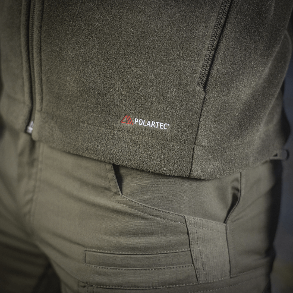 Lähikuva M-Tac Nord Polartec -fleecetakista Polartec®-logolla, näyttää takin harmaan mdl-värin yksityiskohtia.