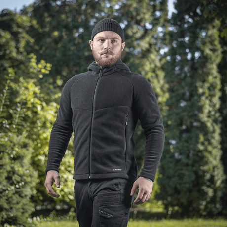 Mies pukeutuneena M-Tac Sprint Fleece Sweatshirt Polartec mustana, seisoo ulkona puiden edessä.