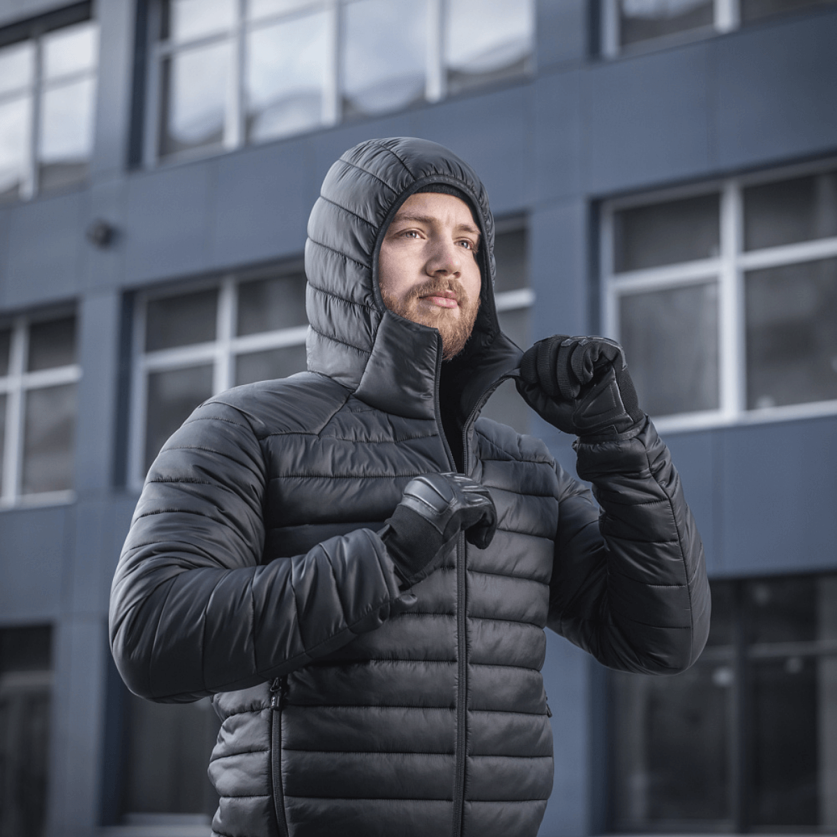 Mies pukeutuneena M-Tac Stalker Gen.III -takkiin modernin rakennuksen edessä