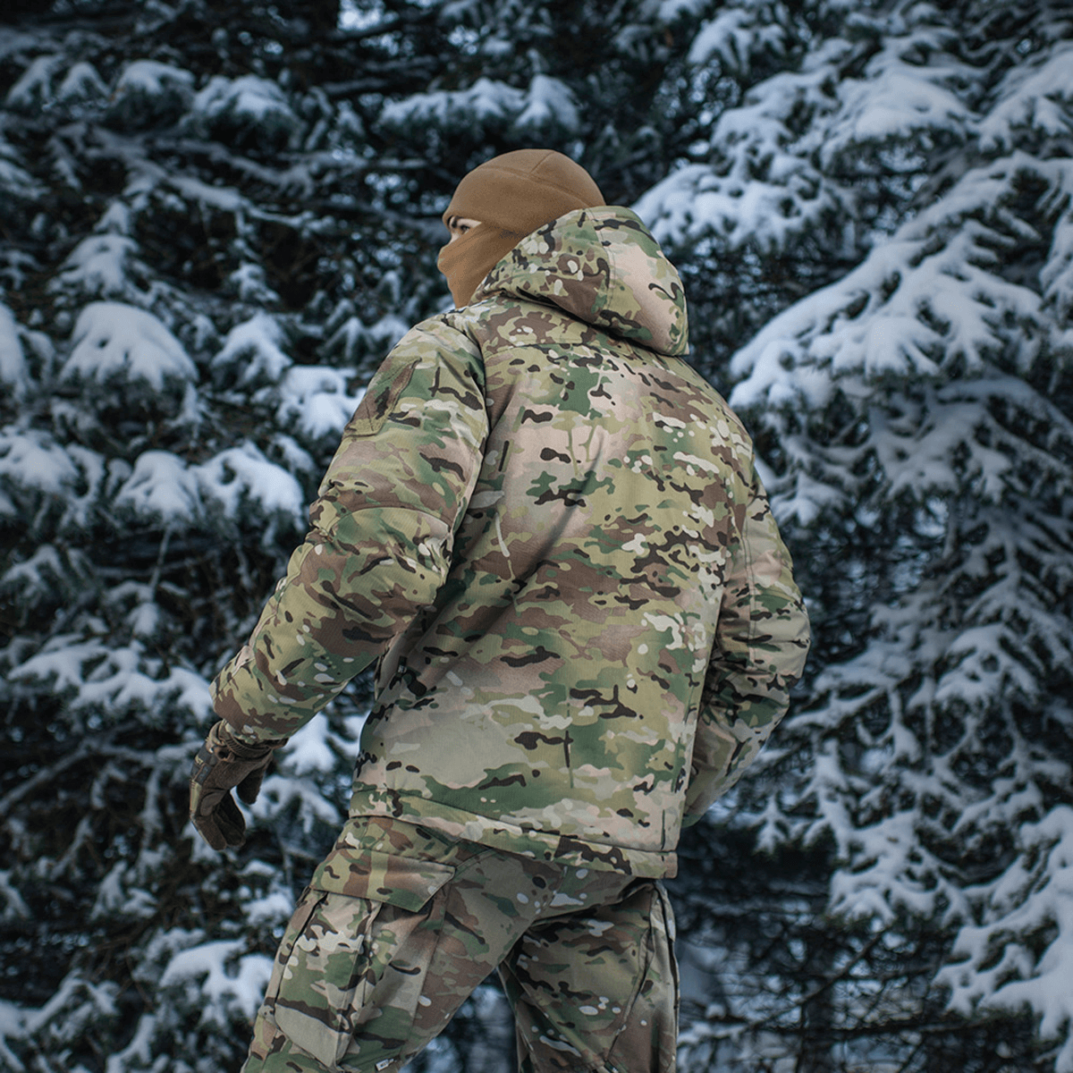 M-Tac Alpha Gen.IV Pro Primaloft -talvitakki lumipeitteisessä metsässä Multicam-designilla, tarjoaa äärimmäistä kestävyyttä ja kylmäsuojaa.